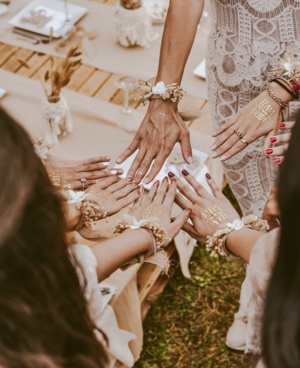 Women at a bridal shower or bachelorette party stretching their hands out together in a ring. They have TEAM BRIDE written on the back of their hands.
